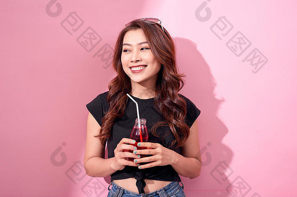 肖像美丽的快乐可爱的女人女孩休闲夏天衣服喝红色的苏打水水瓶稻草粉红色的背景