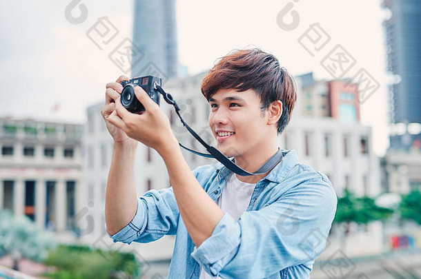 年轻的亚洲男人。旅游采取照片户外城市