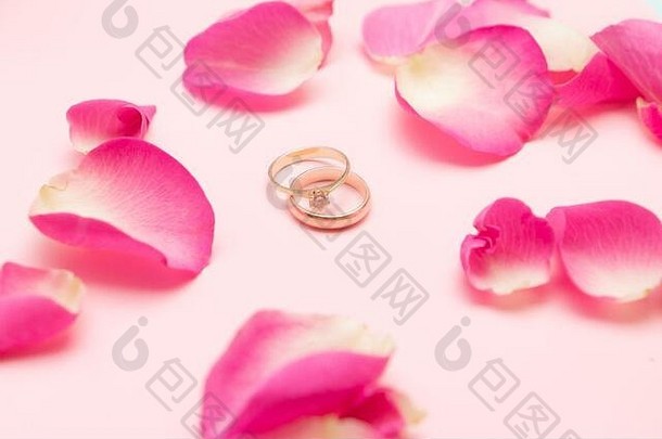婚礼环黄金订婚环宝石玫瑰花瓣柔和的粉红色的背景婚姻概念快乐情人节一天