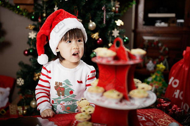 蹒跚学步的婴儿女孩吃老鼠馅饼前面圣诞节树