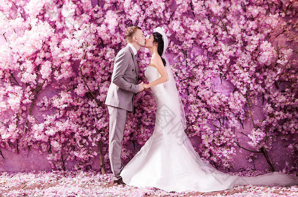 一边视图婚礼夫妇接吻白色站墙覆盖粉红色的花