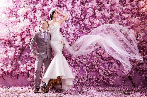 完整的长度婚礼夫妇站墙覆盖粉红色的花