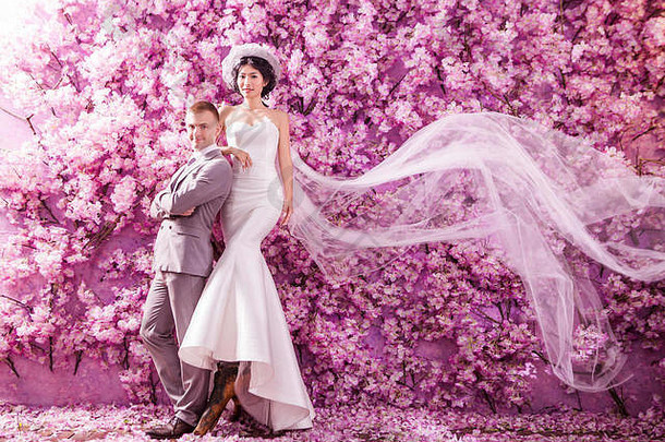 肖像自信婚礼夫妇站墙覆盖粉红色的花