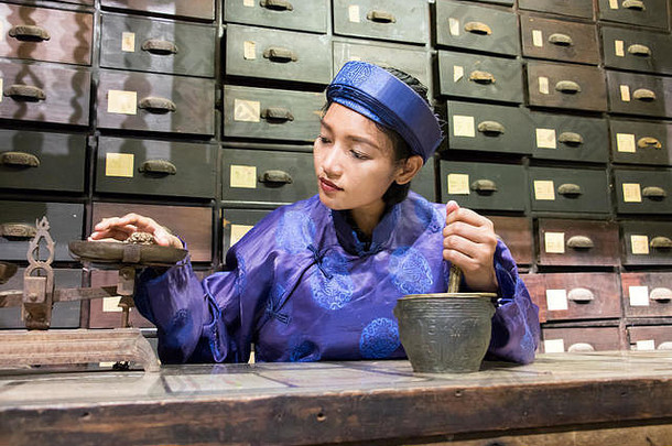 亚洲药剂师工作东方药店世纪女人传统的服装东部药剂师古老的药物商店