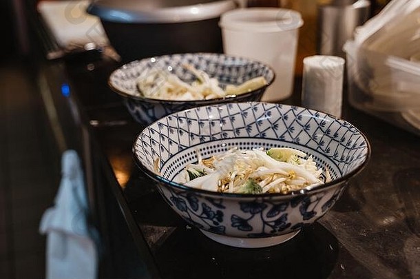 选择焦点视图准备大米面条豆发芽蔬菜碗中国人蓝色的模式计数器餐厅的厨房