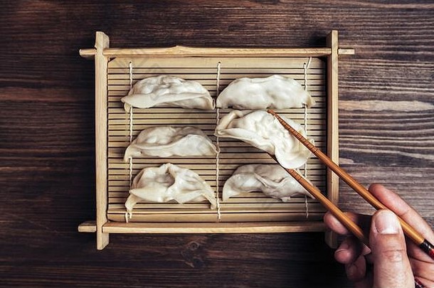 前视图细节手筷子持有饺子竹子托盘黑暗木表格概念健康的东方快食物选取