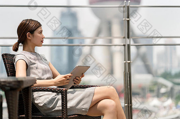 年轻的女商人数字平板电脑人行道上咖啡馆上海金融中心上海中国