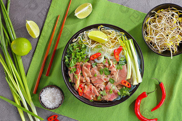 越南汤巨像大米面条生牛里脊肉牛肉片豆豆芽石灰春天洋葱黑色的碗筷子热辣椒绿色