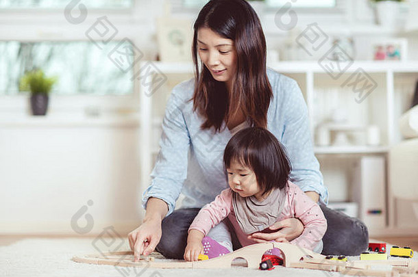漂亮的日本女人玩可爱的笑婴儿女孩地板上首页