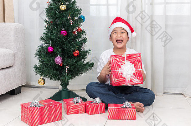 亚洲中国人男孩持有圣诞节礼物盒子生活房间首页