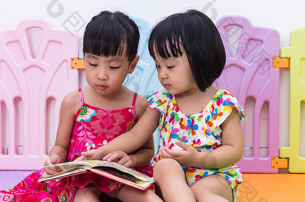 亚洲中国人姐妹坐着地板上阅读首页