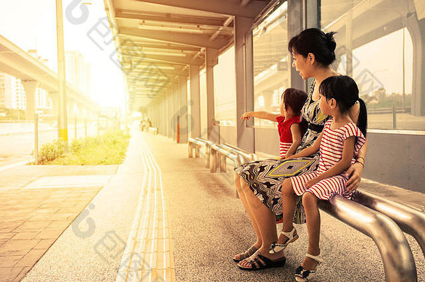 亚洲中国人妈妈。女儿等待公共汽车公共汽车停止