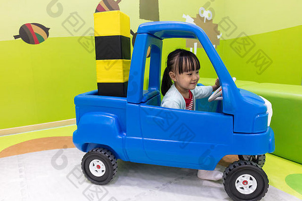 亚洲中国人女孩开车玩具车室内操场上
