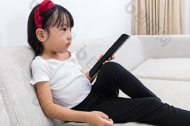 亚洲中国人女孩持有远程控制坐着沙发生活房间首页
