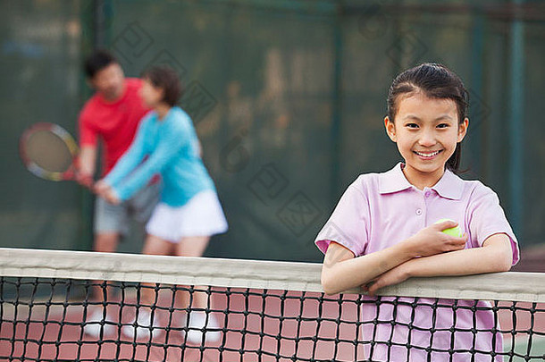 女儿站网球网父母玩背景