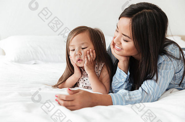 关闭肖像微笑快乐的亚洲女人说谎女儿床上采取自拍