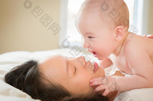 年轻的混合比赛中国人高加索人婴儿男孩铺设床上妈妈。