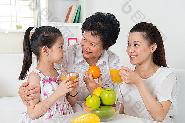 亚洲家庭喝橙色汁快乐亚洲祖父母父孙子享受杯新鲜的挤压水果汁首页