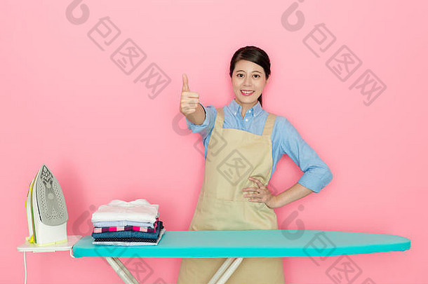 快乐美丽的女房子工人显示拇指手势相机完成了熨衣服家庭服装孤立的粉红色的背气