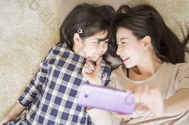 妈妈。自拍女儿聪明的电话相机眼睛联系女儿亚洲家庭概念