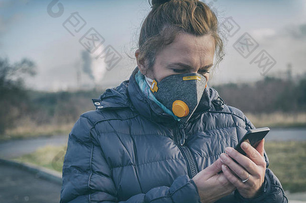 女人穿真正的反污染的anti-smog病毒脸面具检查当前的空气污染聪明的电话应用程序