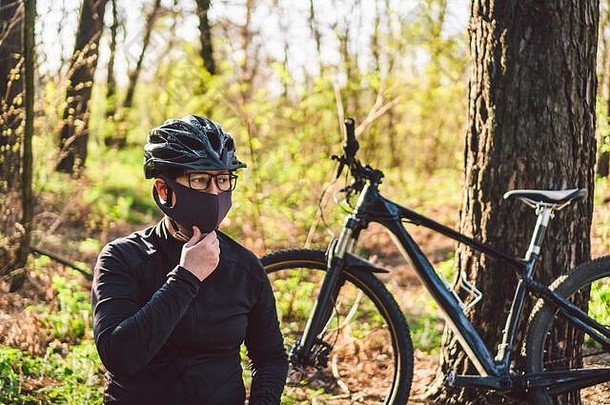 年轻的女人保护面具环境污染骑山自行车森林路骑自行车的人骑自行车小道公园脸污染