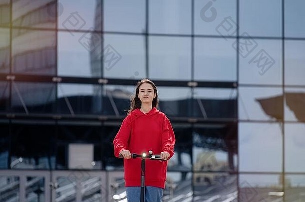 可爱的少年女孩骑电踢踏板车城市景观