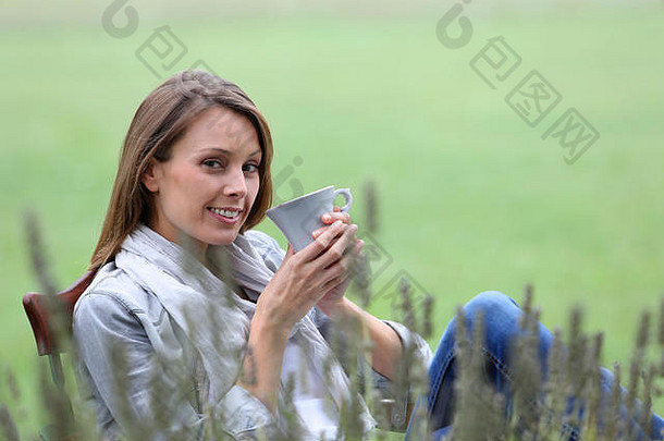 美丽的微笑女人喝热喝花园