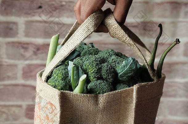 男人的手持有生态友好的可重用的袋新鲜的有机蔬菜