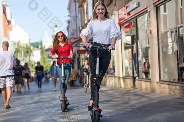 时尚的轻轻松松少年女孩骑公共租赁电摩托车城市城市环境环保现代公共城市运输
