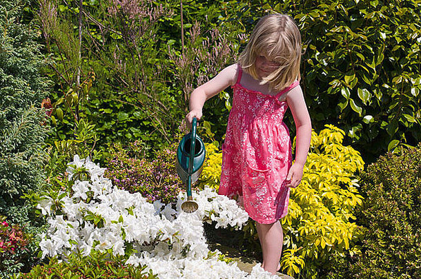 年轻的女孩浇水花花园