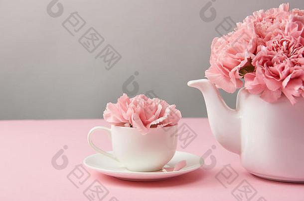 特写镜头视图美丽的温柔的粉红色的花白色茶壶杯灰色
