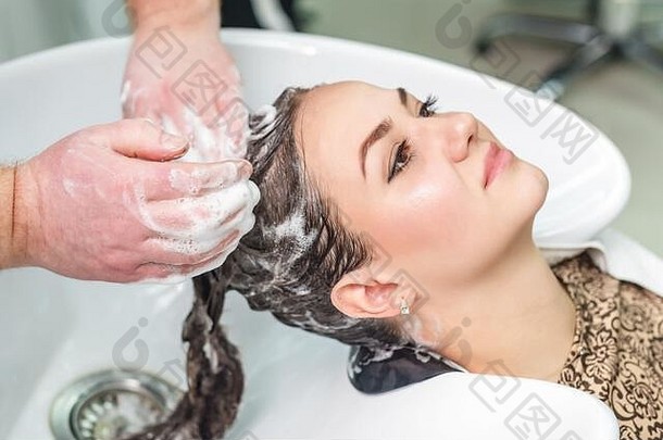 年轻的高加索人女人洗头发水槽美沙龙