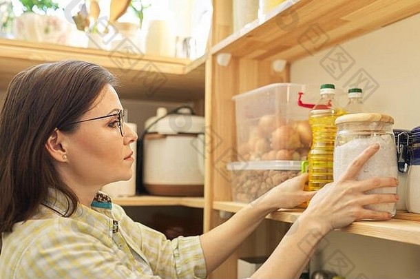 食物存储木架子上储藏室产品女人采取食物向日葵石油烹饪