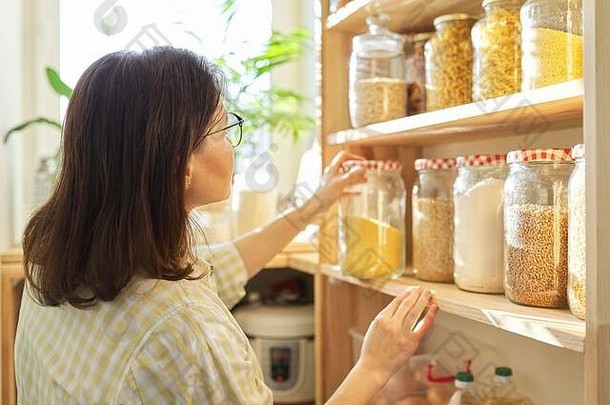 食物存储木架子上储藏室粮食产品存储罐子女人采取食物烹饪
