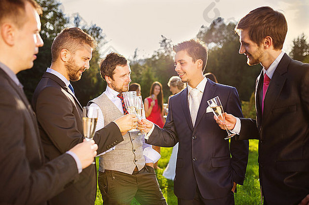 新郎和四个快乐的伴郎在外面的婚宴上举杯