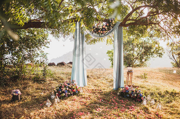 日落婚礼仪式拱装饰灰色布挂大树玫瑰花安排