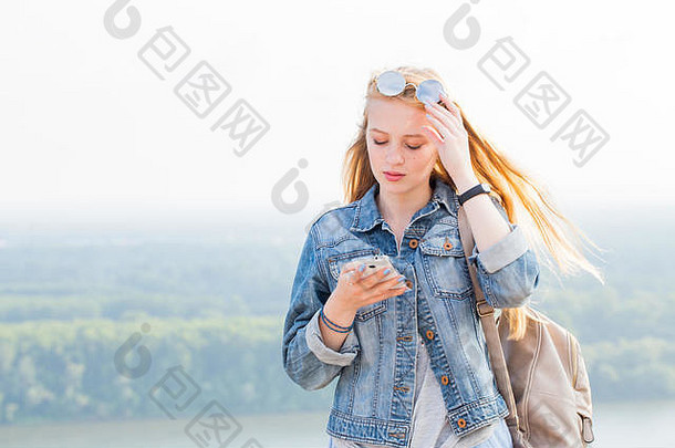 年轻的金发女郎女人阅读消息智能手机自然互联网技术概念