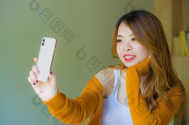 年轻的有吸引力的放松亚洲朝鲜文女孩移动电话首页卧室享受互联网在线视频调用社会媒体应用程序坐着