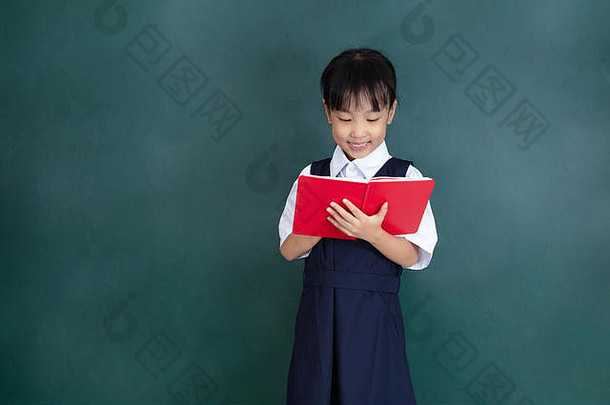 亚洲中国人女孩统一的阅读书绿色黑板上教室