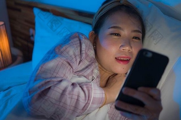 睡觉前生活方式肖像年轻的美丽的快乐甜蜜的亚洲中国人女人头巾睡衣享受手电话床上晚上