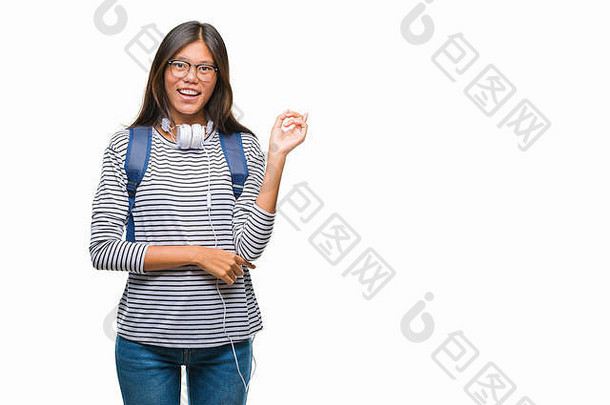年轻的亚洲学生女人穿耳机背包孤立的背景大微笑脸指出手手指一边