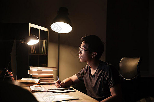 集中亚洲年轻的男人。眼镜电脑研究写作记事本晚上首页