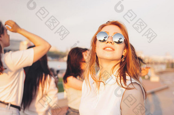 积极的美丽的快乐红色的头发的女孩镜子太阳镜朋友蓝色的天空背景夏天日落时间