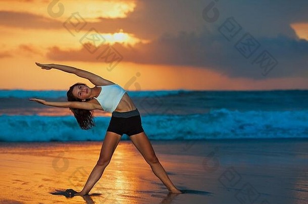 运动型年轻的女人<strong>锻炼</strong>伸展运动上升手脚日落海滩天空背景健康的生活方式热带岛瑜伽