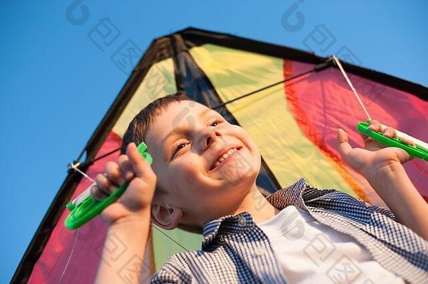 健康的微笑令人愉快的孩子衬衫持有色彩斑斓的风筝蓝色的夏天日落天空背景