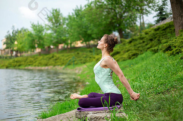 纤细的高加索人浅黑肤色的女人女孩瑜伽夏天绿色草坪上河