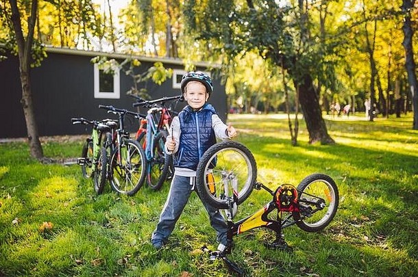 高加索人孩子男孩头盔学习修复自行车孩子骑自行车的人检查机制自行车清算绿色草公园