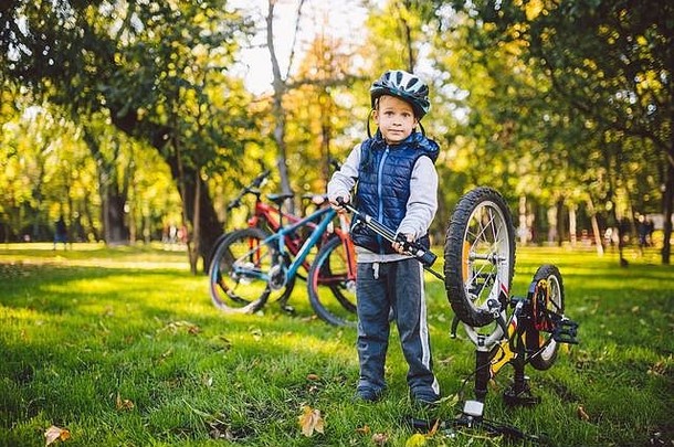 高加索人孩子男孩头盔学习修复自行车孩子骑自行车的人检查机制自行车清算绿色草公园