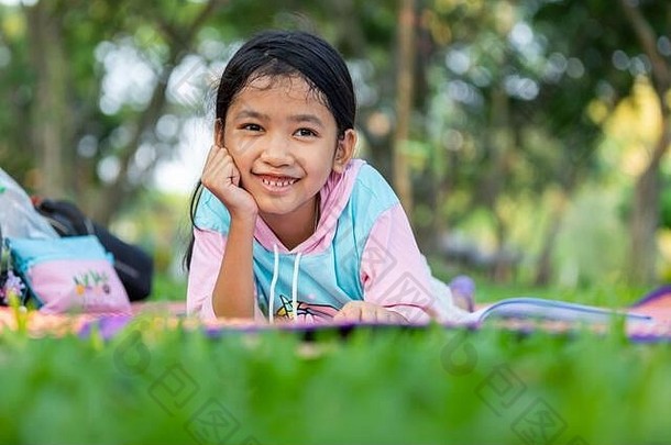亚洲女孩躺把手下巴微笑草坪上花园孩子阅读书假期picni